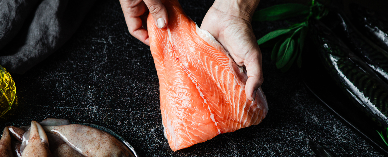 Filetto di salmone fresco tenuto tra le mani